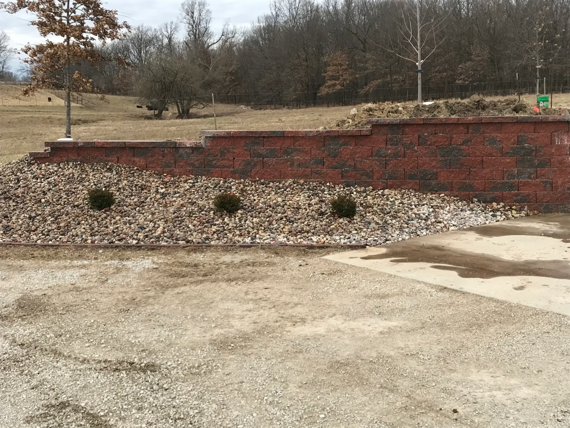 A large brick wall in the middle of an empty lot.