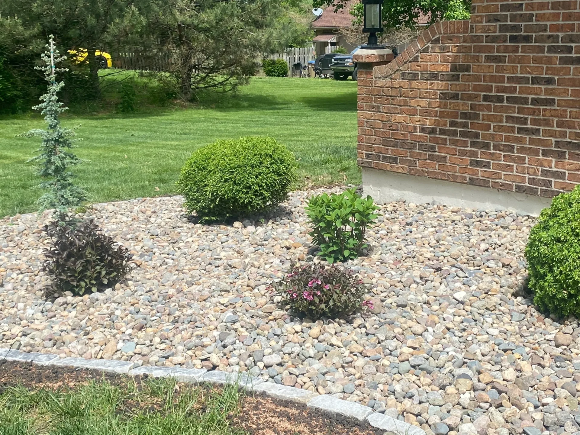 A garden with bushes and rocks in the yard.
