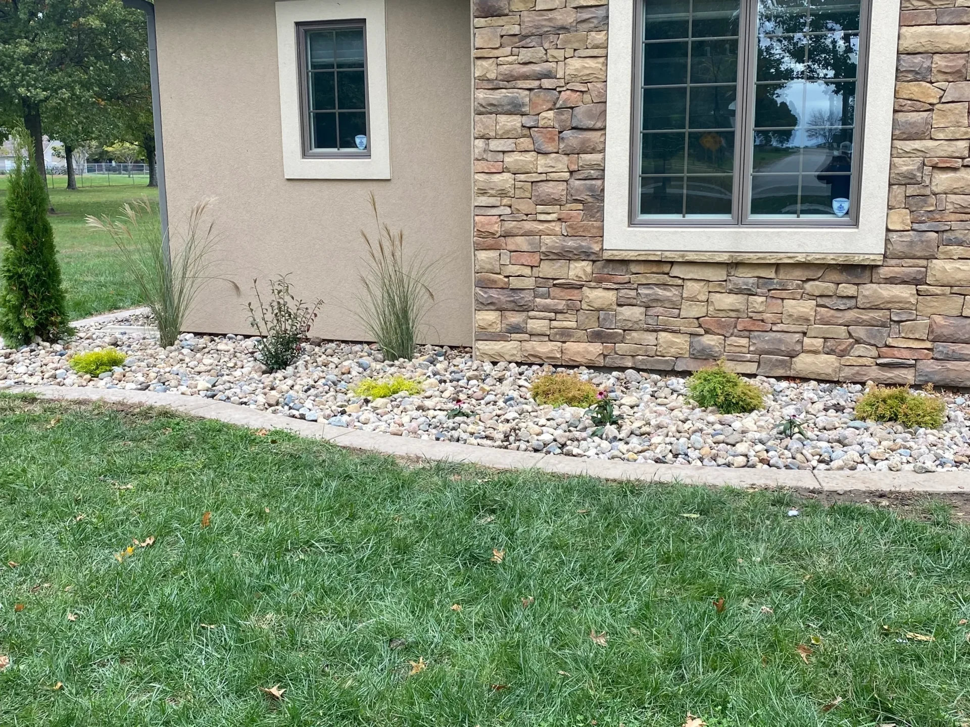 A yard with grass and rocks in the front of it