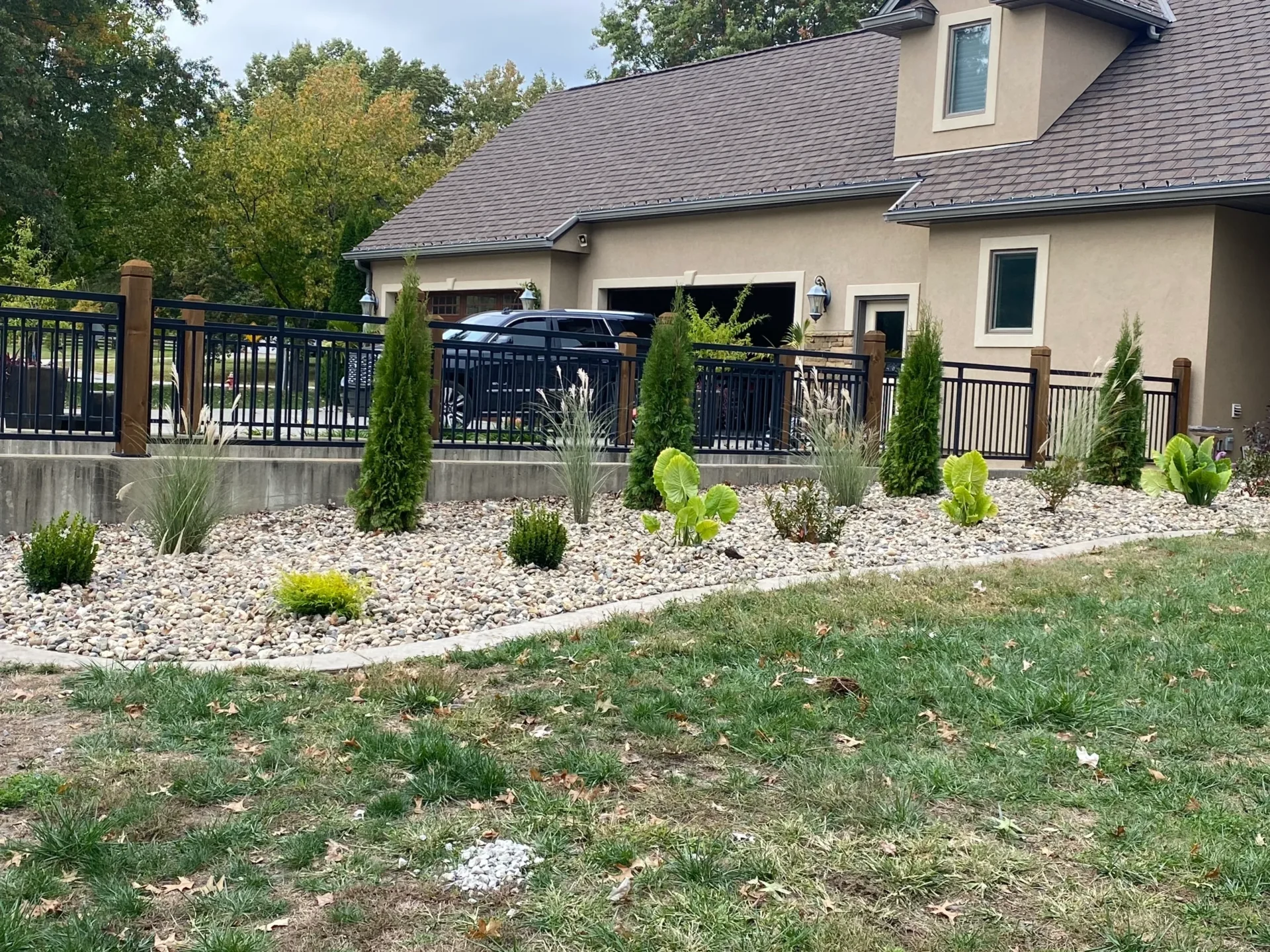 A yard with a fence and bushes in the background.