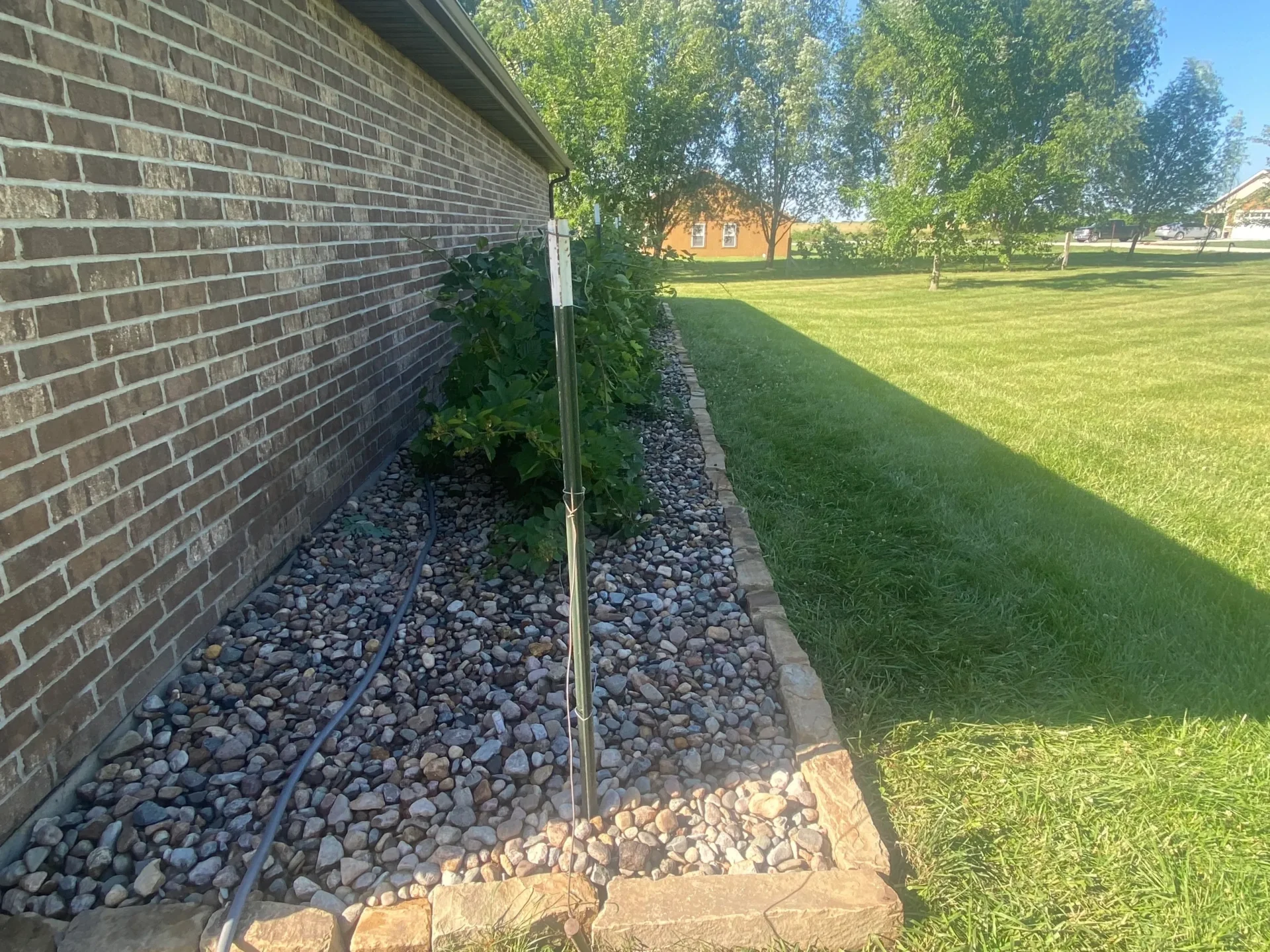A stone wall and grass in the corner of a yard.