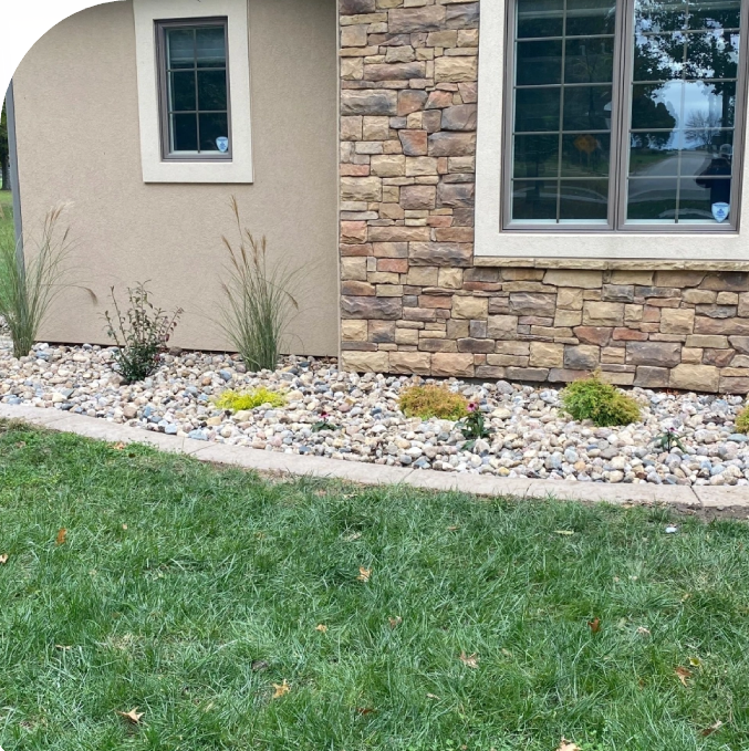 A yard with grass and rocks in the front of it.